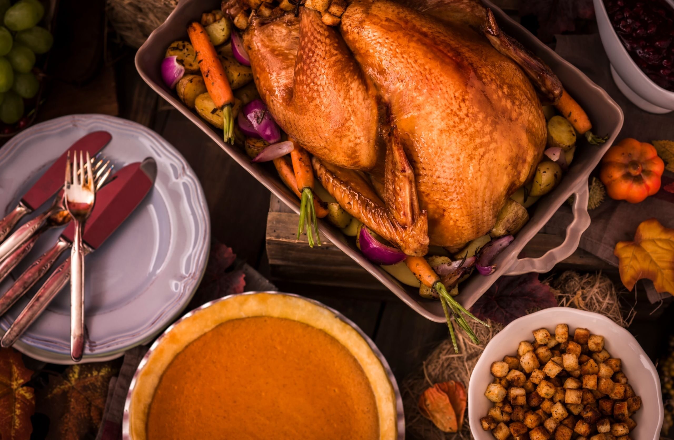 turkey on Thanksgiving day with stuffing on a table with dishes and pumpkin pie