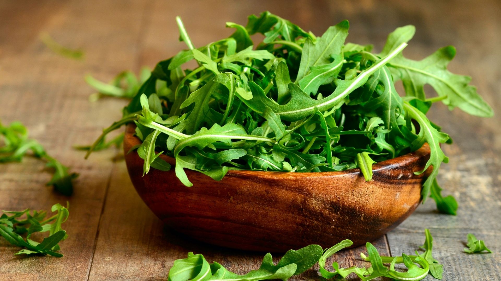 arugula sitting full in a wooden bowl on a table