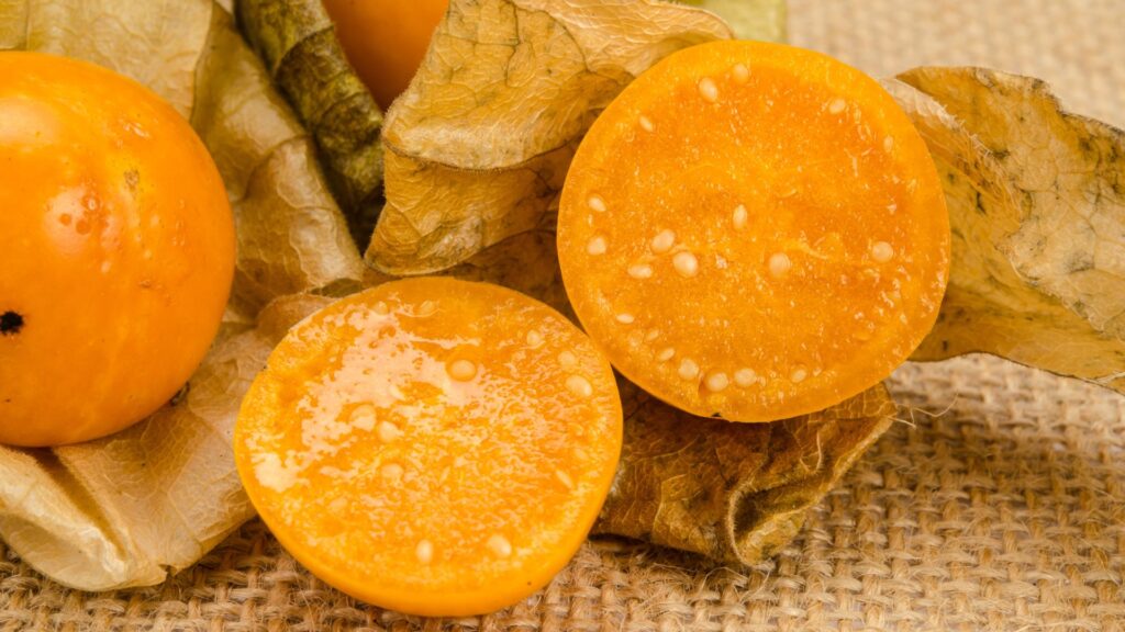 caped gooseberries cut open sitting on a burlap table