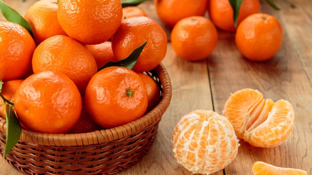 clementine fruit basket sitting on top of a table with some peeled clementine on display