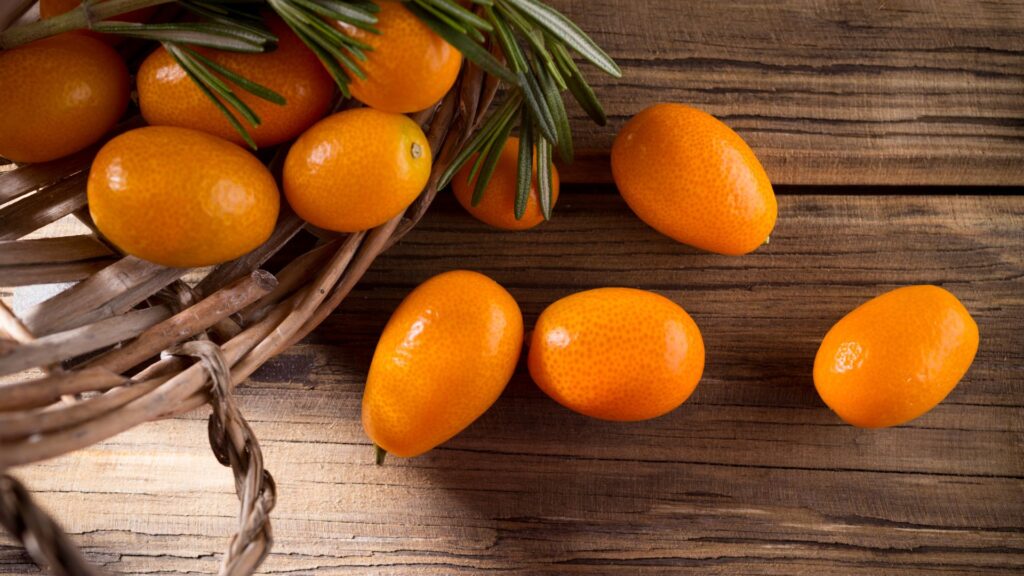 kumquats in a basket with some being displayed on a wooden table