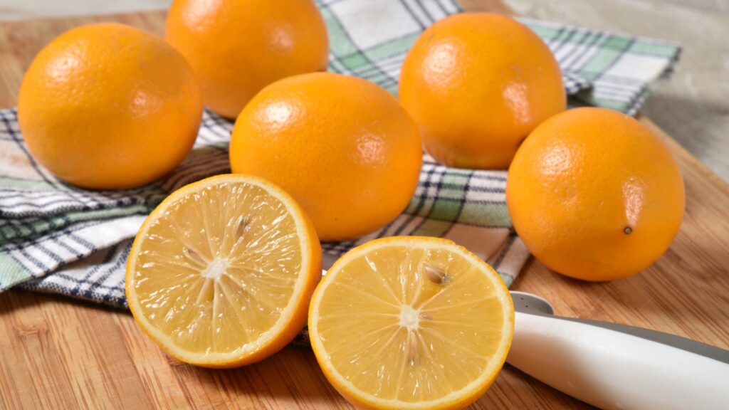 group of meyer lemons sitting on a table with one lemon sliced opened