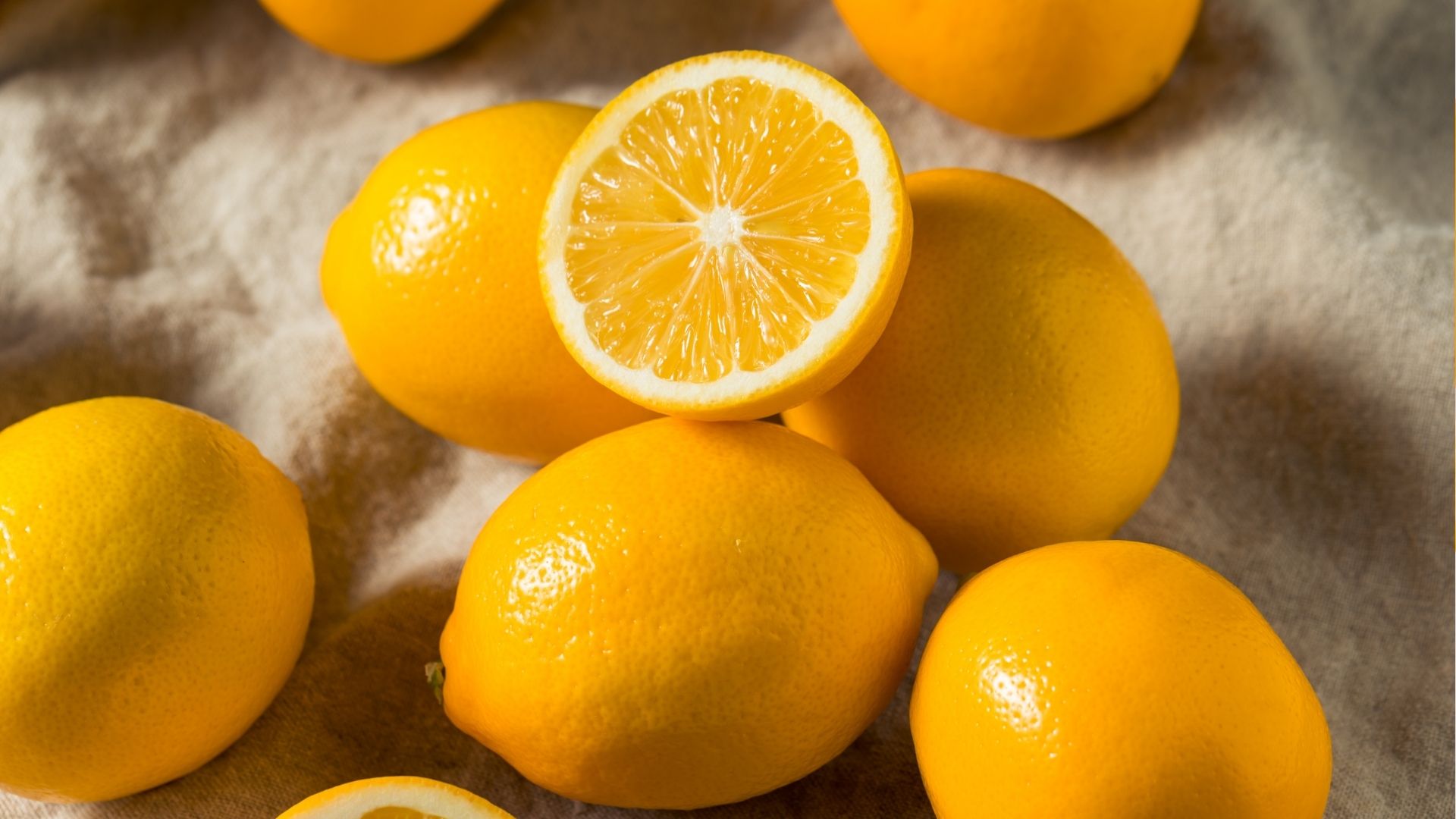 meyer lemons on display on a table with one lemon sliced open to showing the inside