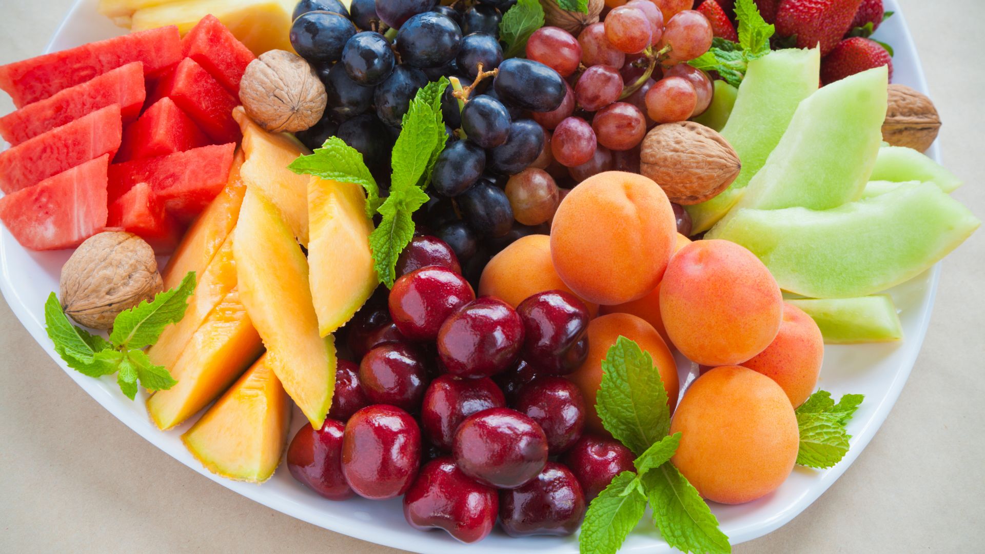 a plate of tasty summer fruits including mangoes, walnuts and berries